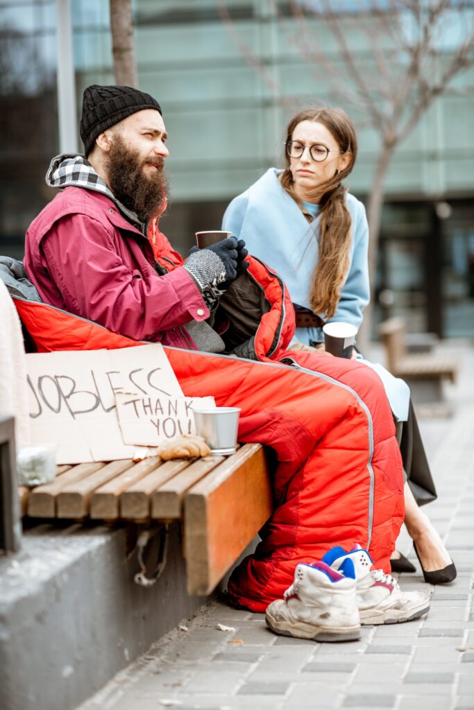 Homeless beggar with young woman listening to his story